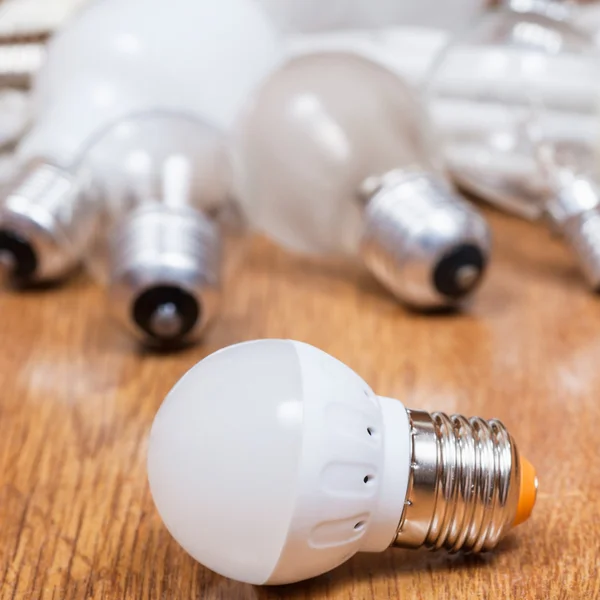 New LED lamp and used bulbs on table — Stock Photo, Image