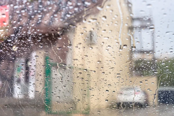 Goteras de lluvia en el parabrisas y la casa borrosa — Foto de Stock