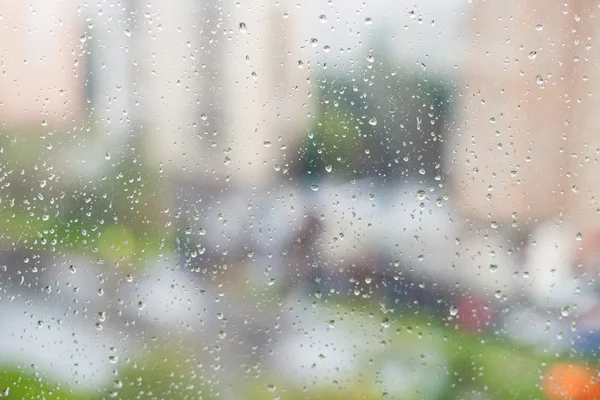 Raindrops on window and blurred houses — Stock Photo, Image