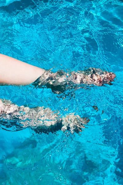 Zampe femminili passere in acqua blu — Foto Stock