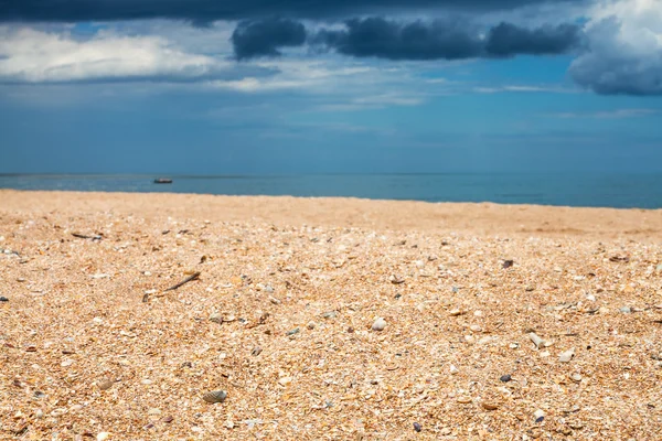 Landschap met zandstrand en donker blauwe regenwolken — Stockfoto