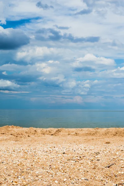 Zand en shelly beach en donker blauwe wolken — Stockfoto