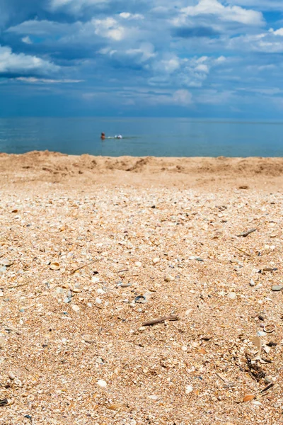 Spiaggia di sabbia e ghiaia da vicino e mare blu scuro — Foto Stock