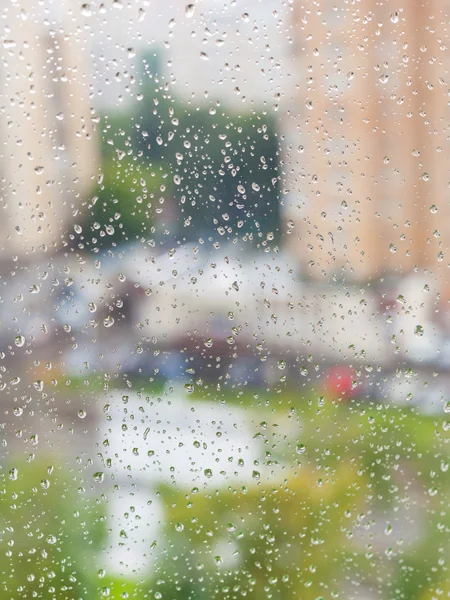 Gotas de lluvia en la ventana y paisaje urbano borroso — Foto de Stock