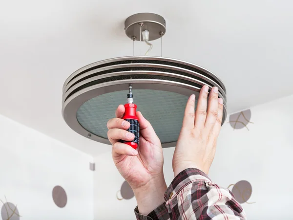 Electrician mounts round ceiling light — Stock Photo, Image