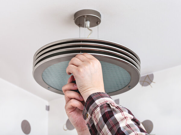 Electrician fixes round ceiling light