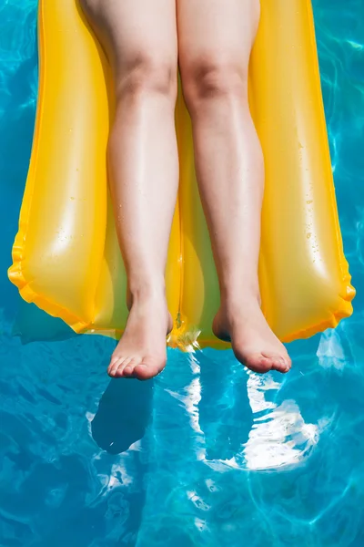 Girl's legs on yellow inflatable mattress — Stock Photo, Image