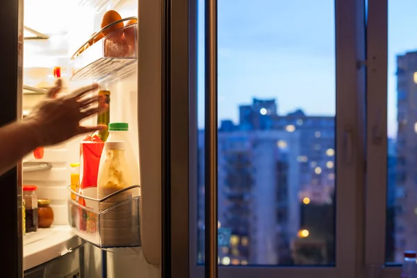Hand når till kylskåp och utsikt över staden — Stockfoto
