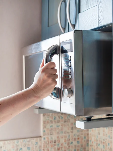 Mão fecha forno de microondas para aquecer alimentos — Fotografia de Stock