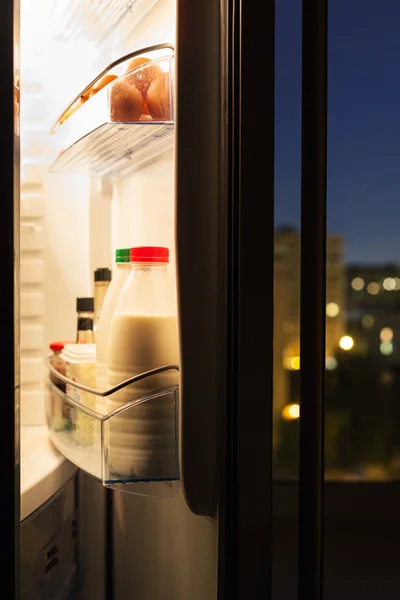 Porta di frigorifero con bottiglie di latte in notte — Foto Stock
