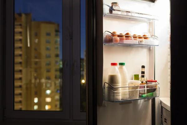 Door of home fridge with dairy products in night — Stock Photo, Image