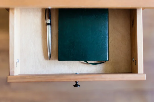 Ручка и ноутбук в открытом ящике — стоковое фото
