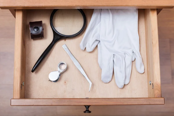 Lupas, pinzas y guantes en el cajón —  Fotos de Stock