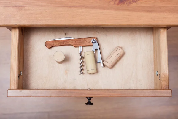 Foldable corkscrew and corks in open drawer — Stock Photo, Image