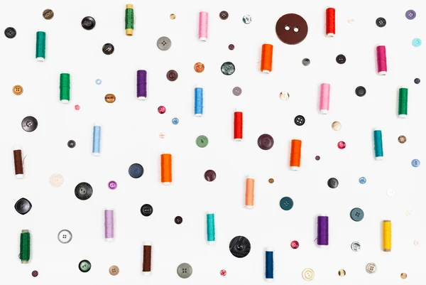 Many spools of thread and various buttons on white — Stock Photo, Image