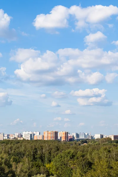 Weiße Wolken am blauen Himmel über der Stadt und grünen Wäldern — Stockfoto