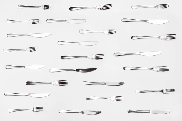 Vista superior de cuchillos y tenedores dispuestos en blanco —  Fotos de Stock