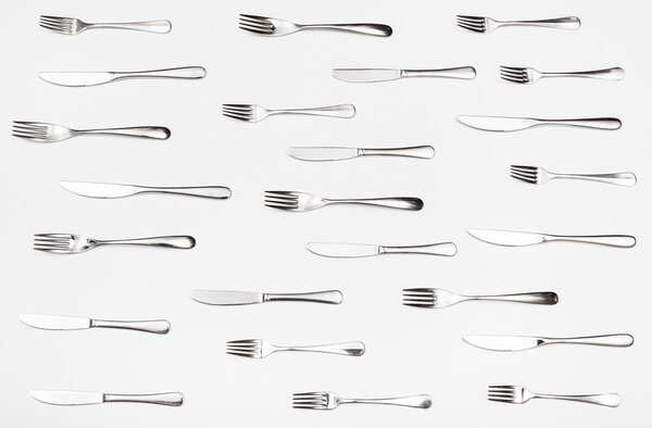 top view of many table knives and forks on white