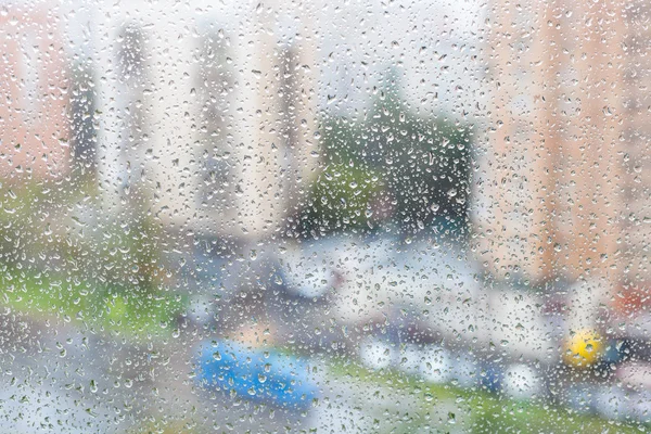 Weergave van regendruppels op windowpane van stedelijke huis — Stockfoto