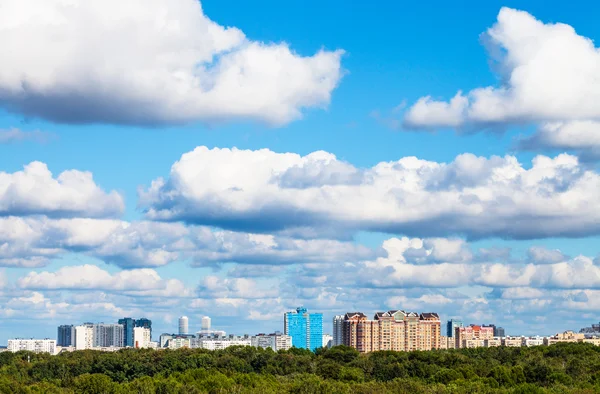 Lage witte wolken in blauwe hemel over stad in de zomer — Stockfoto