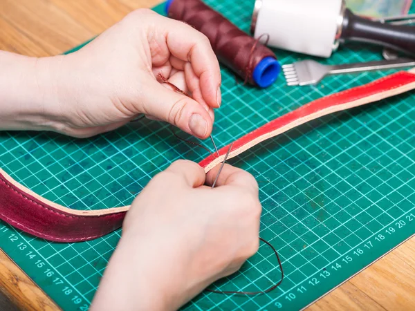 Skinner sews new leather belt — Stock Photo, Image