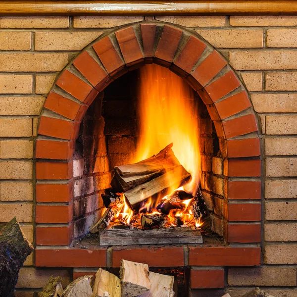 Wood burning in indoor brick fireplace — Stock Photo, Image