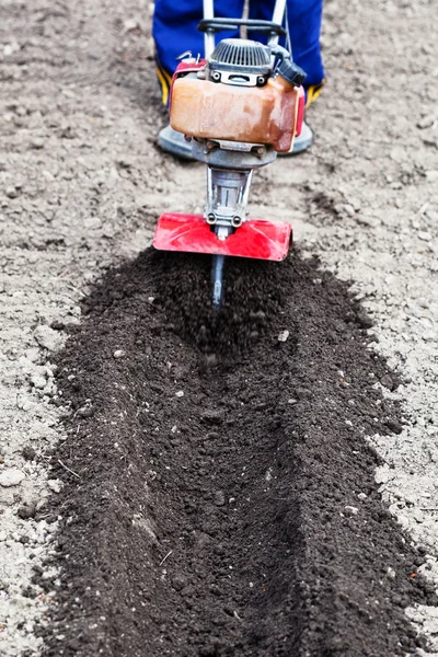 Farmer plows soil in garden by tiller — Stock Photo, Image