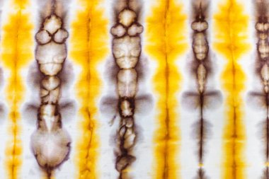 Tekstil arka planı - el yapımı ipek eşarbın beyaz ipek kumaşı üzerinde kravat boyası batik tekniğinde soyut sarı ve kahverengi dekoru