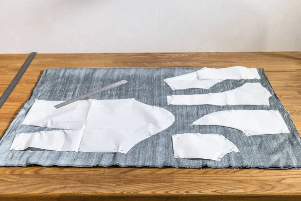 Paper layouts of sewing patterns of dress on gray fabric and steel rulers on wooden table at home — Stock Image Paper Layouts Sewing Patterns Dress Gray Fabric Steel Rulers Wooden Stock Image