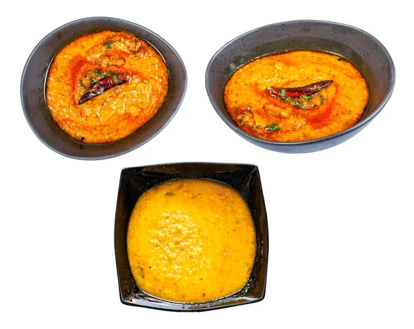set of Dal Tadka (spicy smooth and creamy chowder from lentils with curry) in black bowl isolated on white background