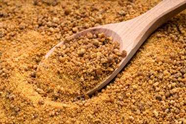 Tahta kaşığın üstünde granüle hindistan cevizi çiçeği çiçeği şekeri var. Şeker yığınına yakın.