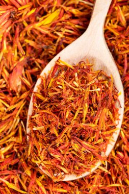 Kurumuş safran yapraklı ahşap kaşık kurumuş çiçek yığınına yakın.