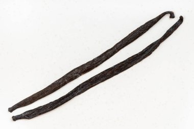 Beyaz tabakta iki farklı vanilya fasulyesi (tahiti vanilyası ve burbon vanilyası).