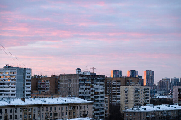 Pink clouds in blue sky over apartment houses in Moscow city at dusk