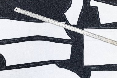 Koyu renk kumaş üzerinde elbise ve çelik cetvel desenlerinin kağıt düzeni