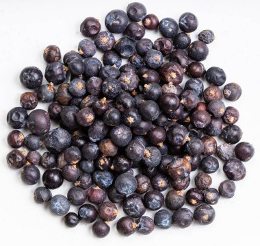 Üstteki kurumuş ardıç meyvesi yığını gri seramik tabağa kapanıyor.