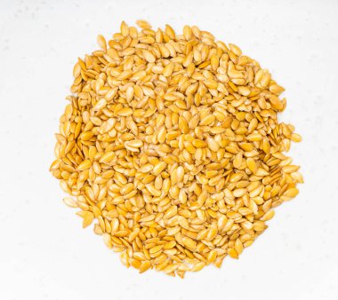 Gri seramik tabağa yakın altın keten tohumlarının üst görüntüsü