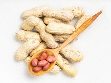 Tahta kaşıkta çekirdeklerin üst görüntüsü ve gri seramik tabakta yer fıstığı yığını