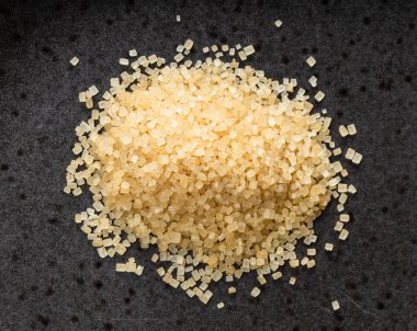 En üstteki demerara kahverengi kamış şekeri yığını siyah seramik tabağa yakın