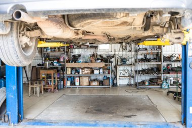 bottom view of lifted old car in car workshop (focus on the muffler in center of car's bottom)