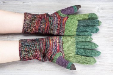 palm view of female hands in knitted gloves on gray table