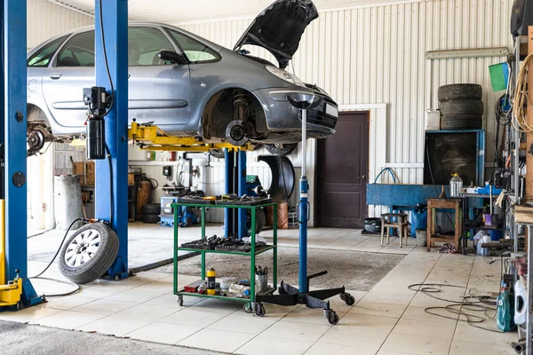 old car is lifted on hydraulic lift in car workshop