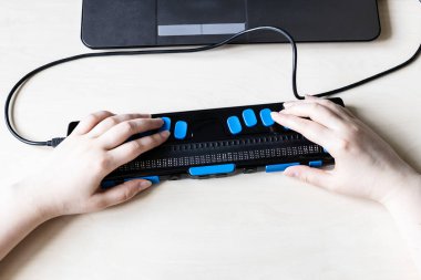 Moscow, Russia - June 5, 2021: hands on keys of Focus 40 Blue Braille Display. Freedom Scientific is the largest manufacturer of assistive technology products for blind and low vision people