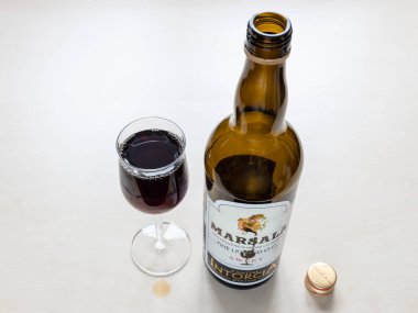 MOSCOW, RUSSIA - JUNE 10, 2021: wineglass and empty bottle of sweet Marsala from Cantine Intorcia. Marsala is fortified wine produced in Marsala city area in Sicily, Italy from 1773