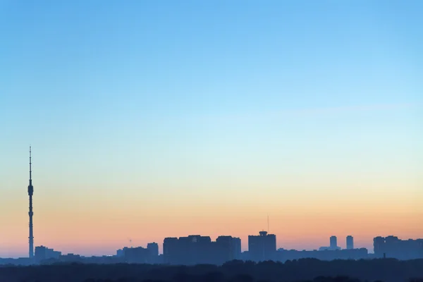 Világos kék és sárga hajnalban ég a város felett — Stock Fotó