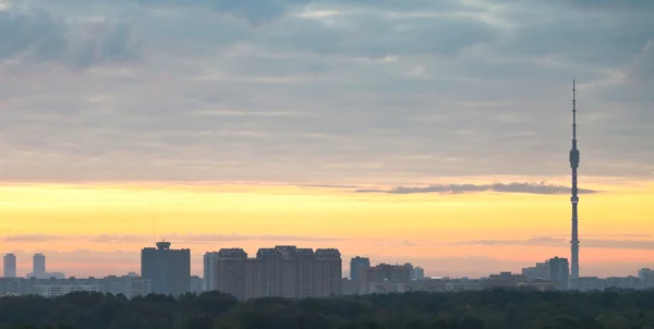 Panorama of city under grey clouds at sunrise — Stock Photo, Image