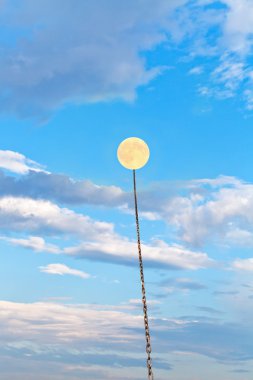full moon tied on chain soars into blue sky clipart