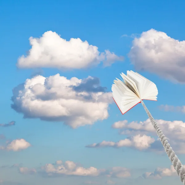 Livre attaché sur corde s'élève en petits nuages blancs — Photo