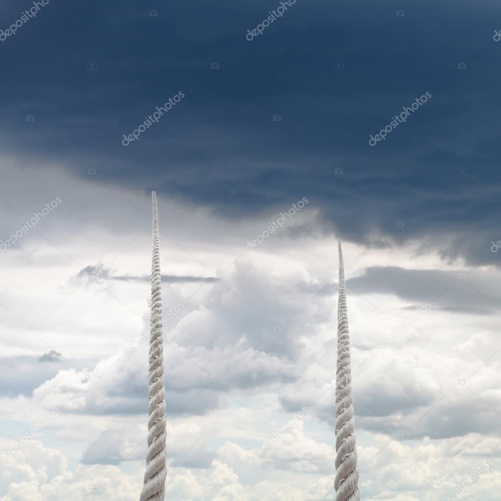 two ropes rise to sky with rainy clouds