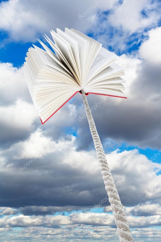 book tied on rope soars into grey clouds